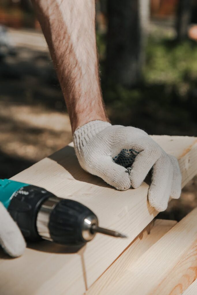 Craftsperson drilling into wood with a power tool outdoors. Perfect for carpentry themes.